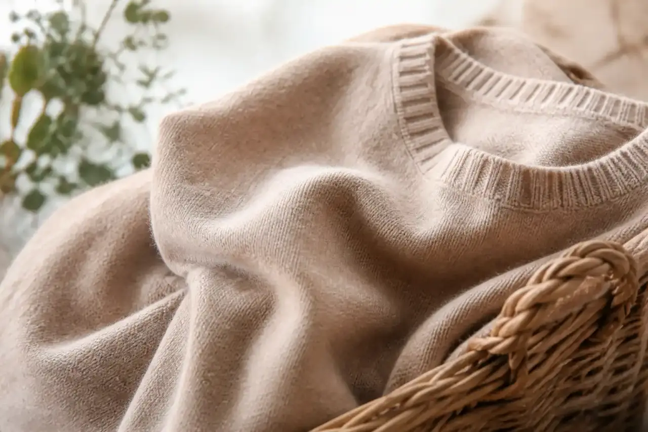 Pull en cachemire vintage plié sur une table en bois clair